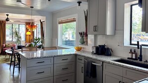 Een moderne keuken met witte kasten, een granieten aanrechtblad en roestvrijstalen apparatuur.