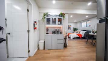 A compact living space with a kitchenette, a bed with a red blanket, and a dining area.