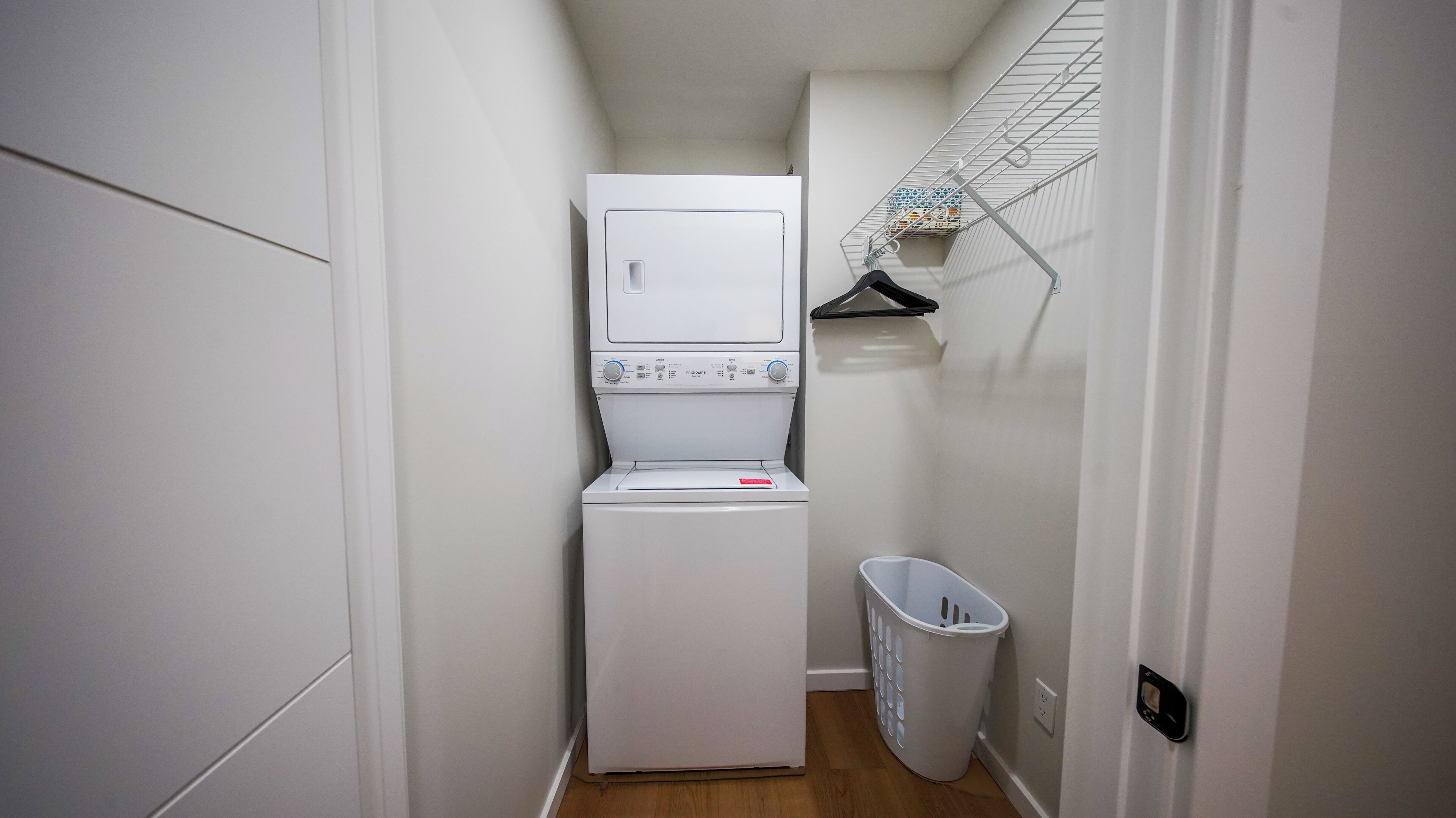 A laundry room with a washing machine and dryer, a drying rack, and a laundry basket.