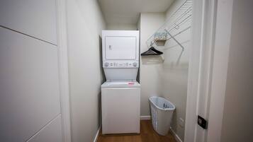 A laundry room with a washing machine and dryer, a drying rack, and a laundry basket.