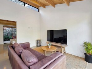 Ein modernes Wohnzimmer mit einer Ledersofa, einem Flachbildfernseher und einem kleinen Holztisch.