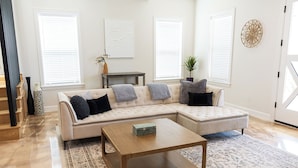 A modern living room with a sectional sofa, a coffee table, and a patterned rug.