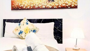 Habitación de hotel con una cama, un cuadro de un árbol y flores, un control remoto y una lámpara.