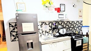 Cocina compacta con refrigerador, estufa, microondas y lavaplatos.