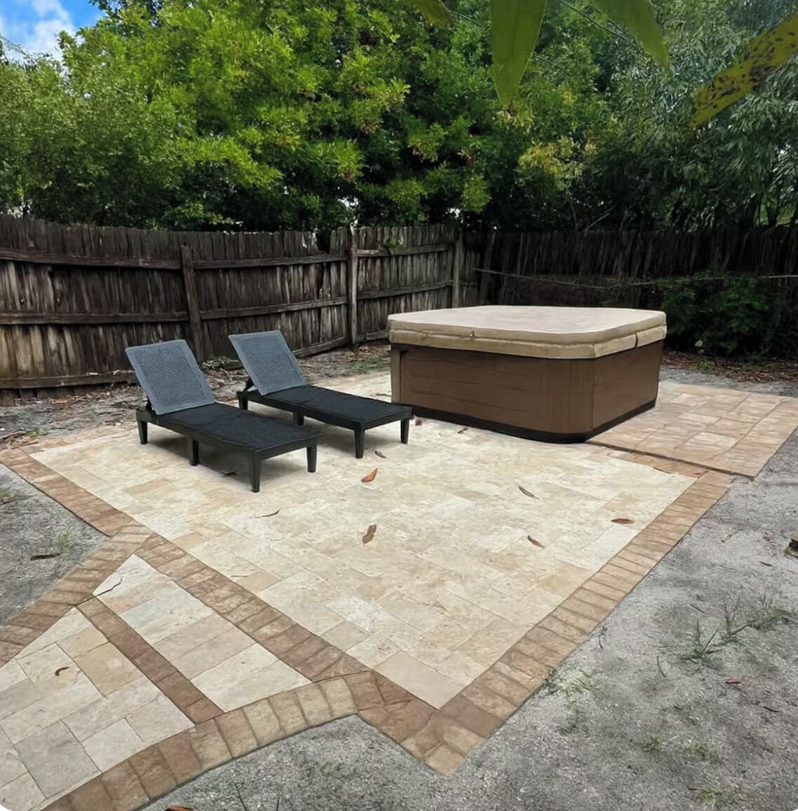 A patio area with two lounge chairs and a hot tub.