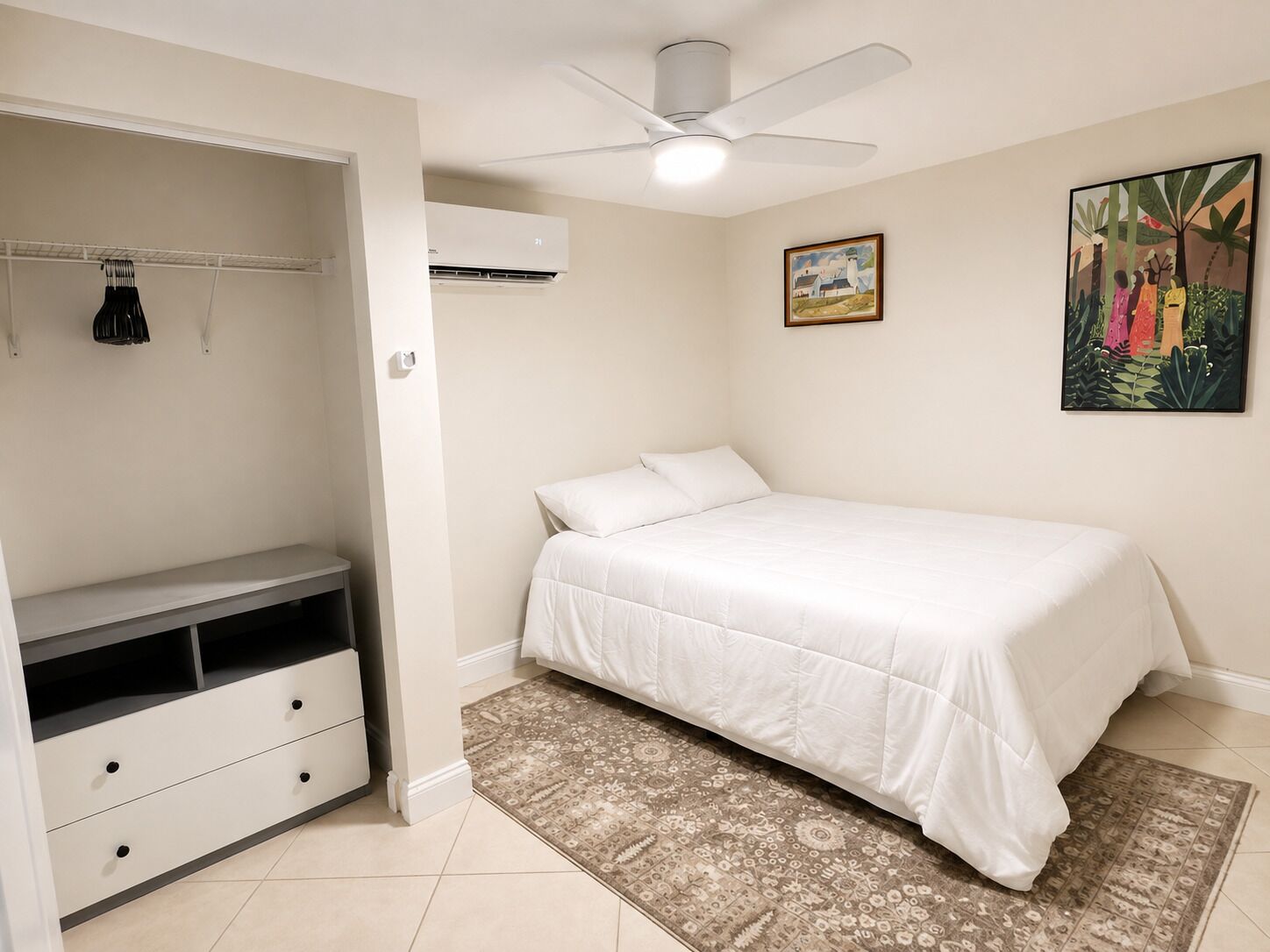 A bedroom with a bed, a wardrobe, a ceiling fan, an air conditioning unit, and a patterned rug.