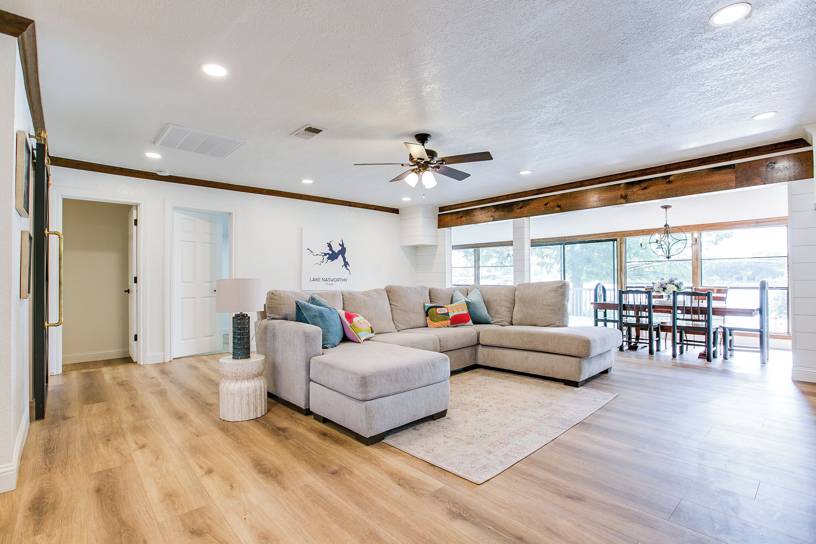 A spacious living room with a sectional sofa, a ceiling fan, and a dining area with a table and chairs.