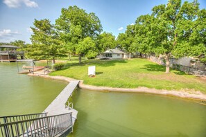 Un quartier résidentiel avec une jetée qui s’avance dans un lac aux eaux verdâtres, entouré d’arbres et bordé d’une petite maison.