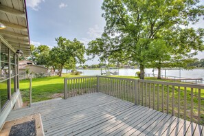 Une terrasse en bois avec une rambarde, une pelouse et une vue sur un lac.