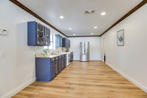 Une cuisine avec un plancher en bois, des armoires bleues et un réfrigérateur en acier inoxydable.