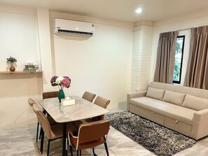Una sala de estar moderna con una mesa de comedor, sillas, un sofá y un tapete estampado.