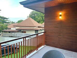 Ein Balkon mit Holzwertkasten, ein geparktes Auto im Hintergrund und Blick auf benachbarte Häuser.