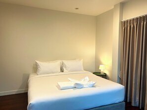 A hotel room with a neatly made bed, a bedside lamp, and a curtain. - 3-bedroom house in adorable Chalong Phuket with nestled among lush mature trees (Tambon Chalong)