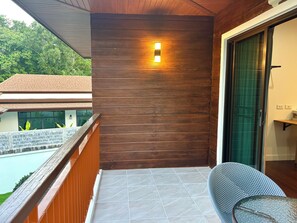 A balcony with a wooden wall, a metal railing, and a chair. - 3-bedroom house in adorable Chalong Phuket with nestled among lush mature trees (Tambon Chalong)