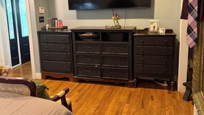Une chambre à coucher avec un grand lit, une commode, un téléviseur et une porte dotée d’une vitre.