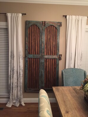 Una stanza con una porta in legno, una panca, un tavolo e una sedia.