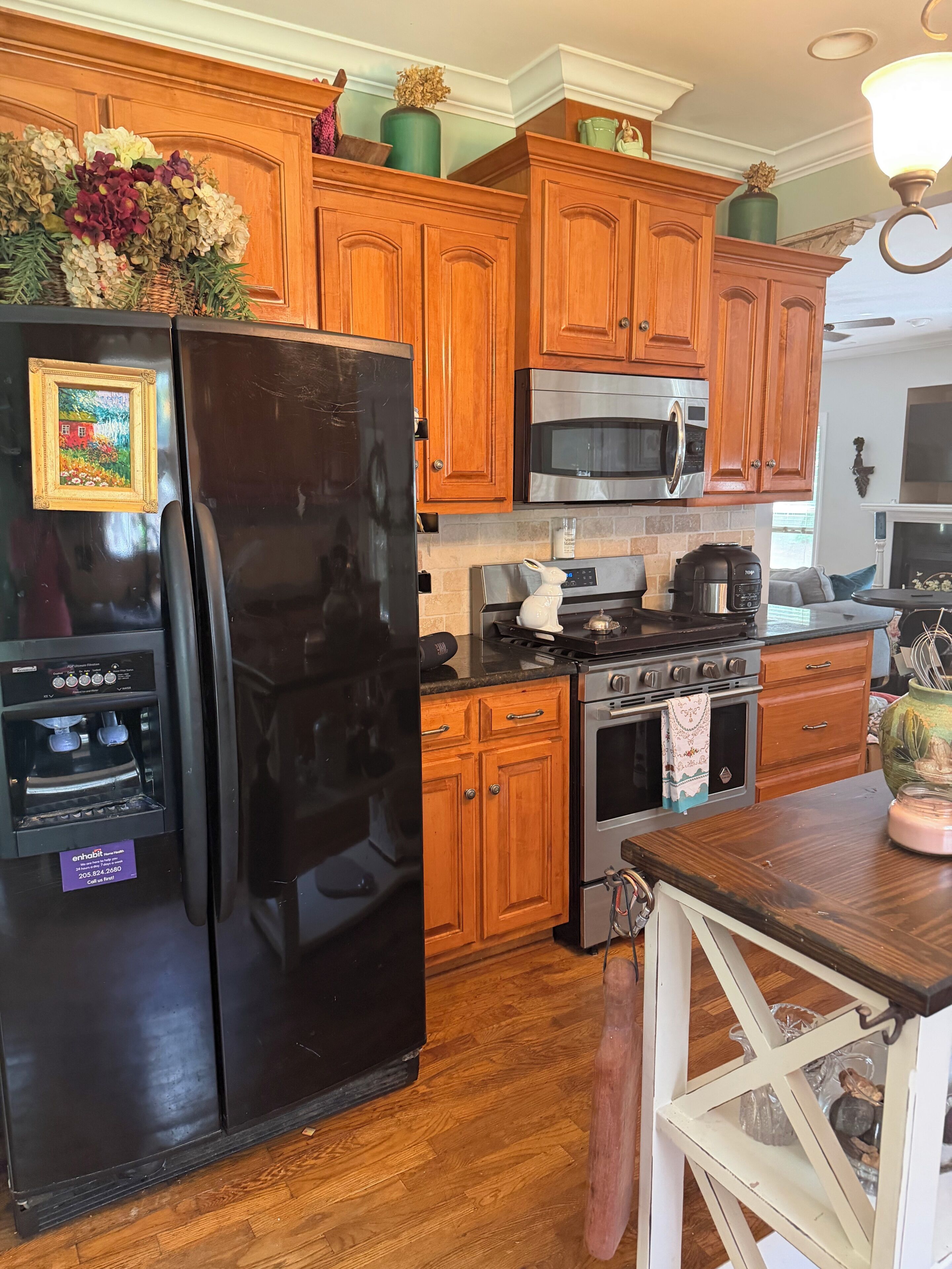 A kitchen with wooden cabinets, a black refrigerator, a microwave, a stove, and a coffee maker.