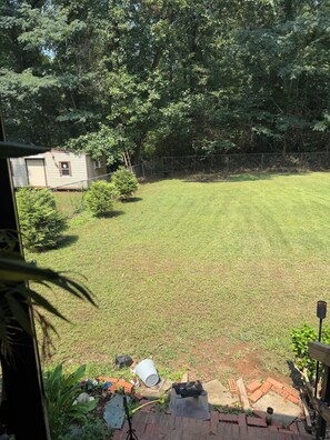 A backyard with a lawn, a small shed, and a wooden fence. - Spacious 4BR Home conveniently located near Birmingham & Tuscaloosa, AL (McCalla)