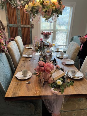 Une table à manger décorée avec des compositions florales, un livre et divers éléments de vaisselle.