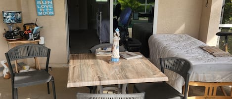 An outdoor patio with a wooden table and chairs, a ceiling fan, and a sign on the wall.