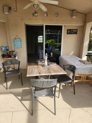 Eine Terrasse im Freien mit einem Holztisch, Stühlen, einem Deckenventilator und einem Schild an der Wand.