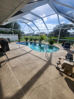 Ein überdachter Außenpool mit Terrassenbereich, inklusive Grill und Fitnessgeräten.