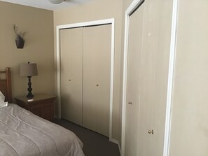 Ein Schlafzimmer mit einem Bett, einem Nachttisch mit Lampe und einem Schrank mit Tür.