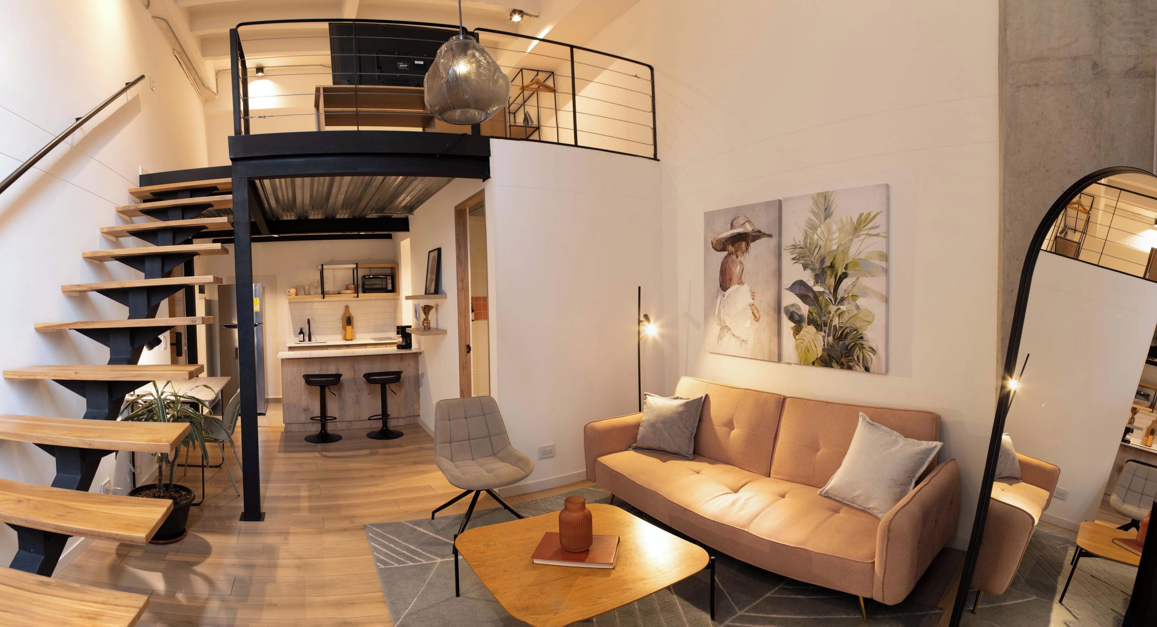 A modern interior with a staircase, a sofa, a dining area, and a kitchen.