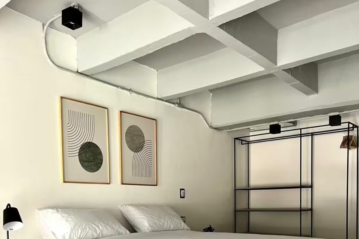 A modern bedroom with a bed, bedside table, and artwork on the wall.