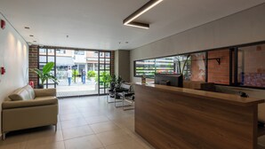 A reception area with a wooden reception desk, a leather sofa, and a large window with a view of the street. - VENTO MOLINO (BELEN)