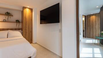 A modern bedroom with a bed, a mounted TV, and wooden paneling.