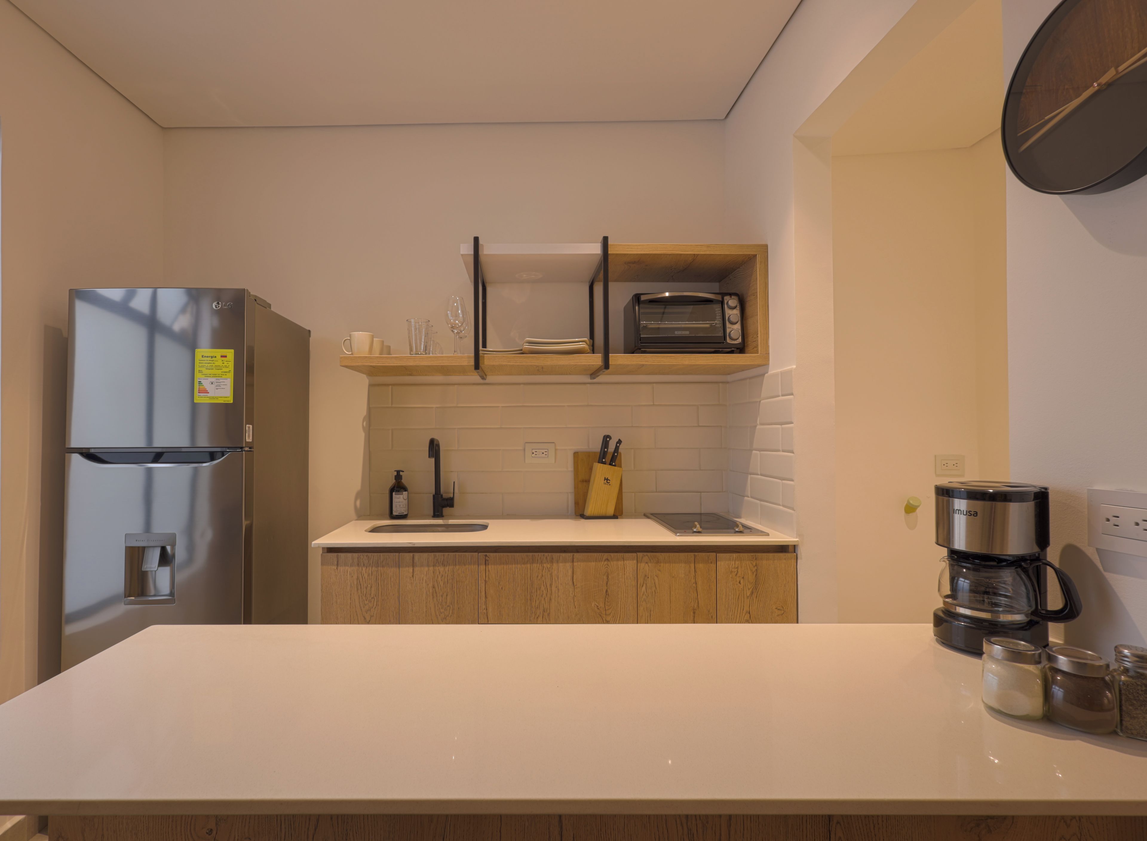 Eine moderne Küche mit integriertem Kühlschrank, einer Toaster-Backofen-Kombination und einer Kaffeemaschine auf der Arbeitsfläche.