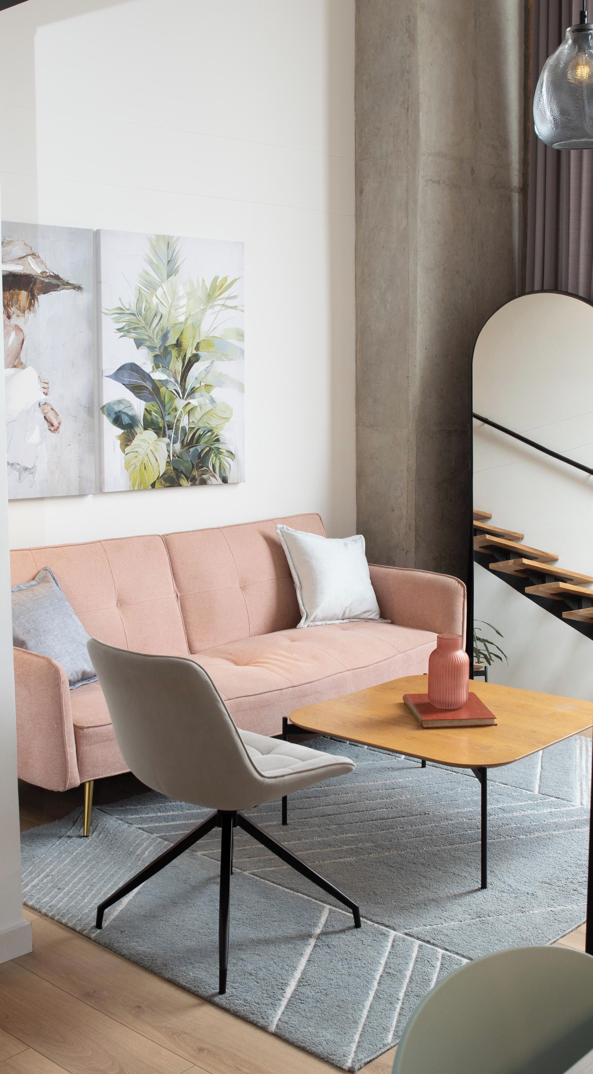 A modern living room with a pink sofa, a white chair, a wooden coffee table, and a large plant.