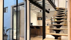 A modern kitchen with a spiral staircase, wooden flooring, and a glass door leading outside. - VENTO MOLINO (BELEN)