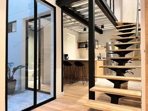 A modern kitchen with a spiral staircase, wooden flooring, and a glass door leading outside. - VENTO MOLINO (BELEN)