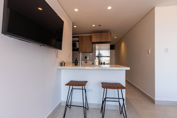 Una cocina moderna con una isla central, dos taburetes de bar y electrodomésticos integrados.