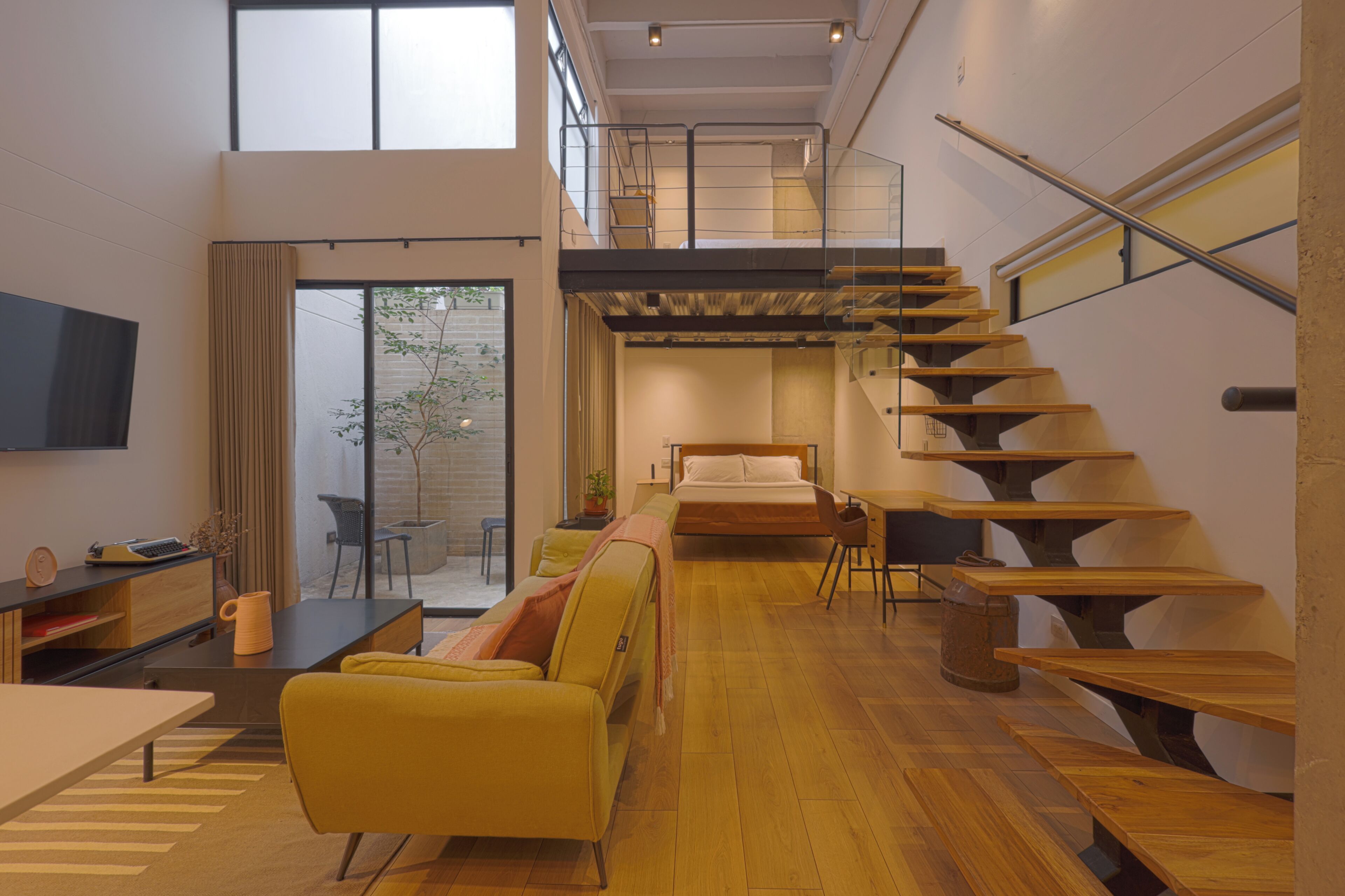 Un intérieur moderne avec une chambre en mezzanine, un coin repas et un escalier.