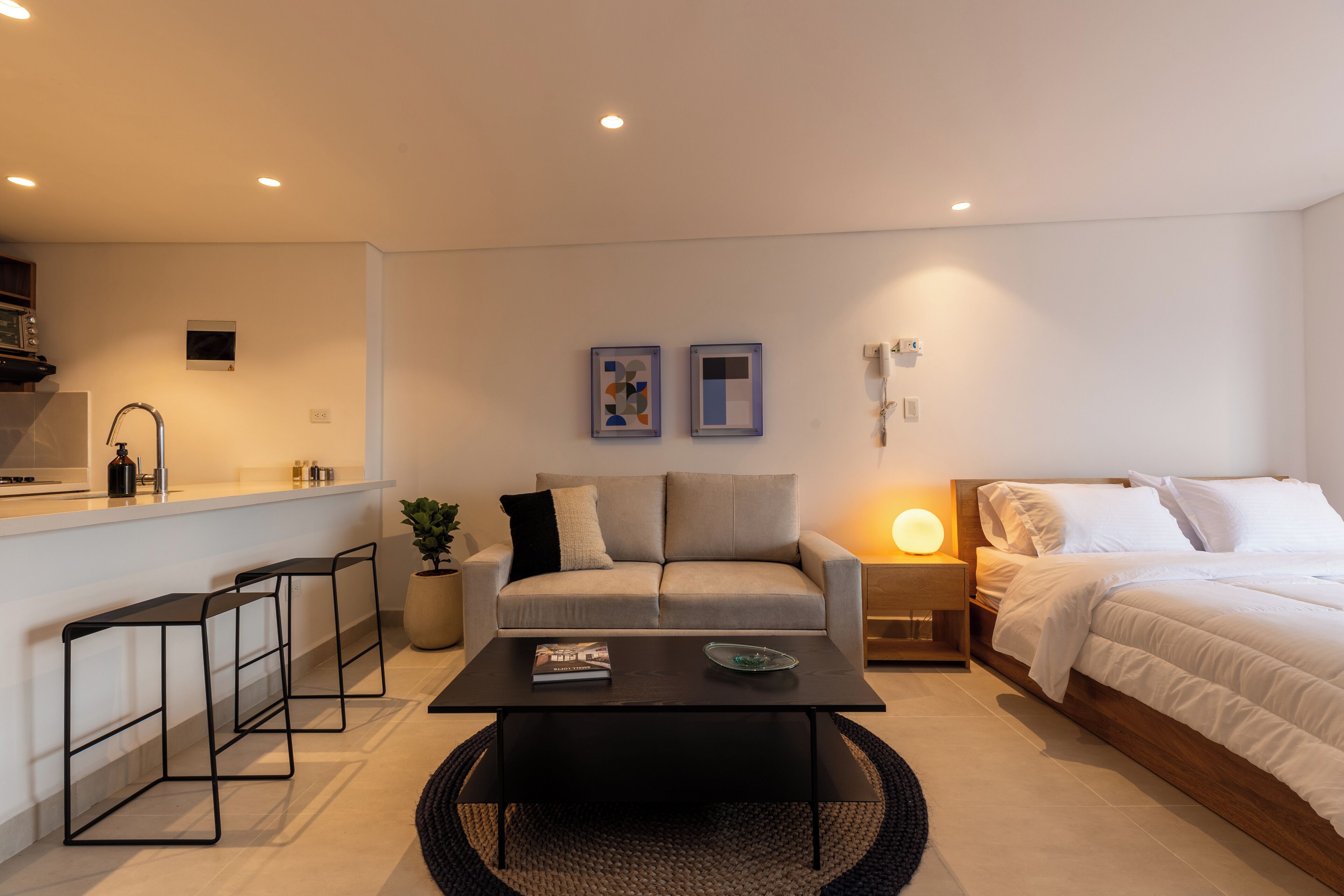 Une chambre à coucher moderne et bien éclairée, avec un lit, une table de chevet et un petit espace bureau.