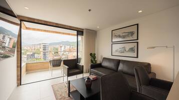 A modern living room with a leather sofa, a coffee table, and a view of a cityscape through large windows.