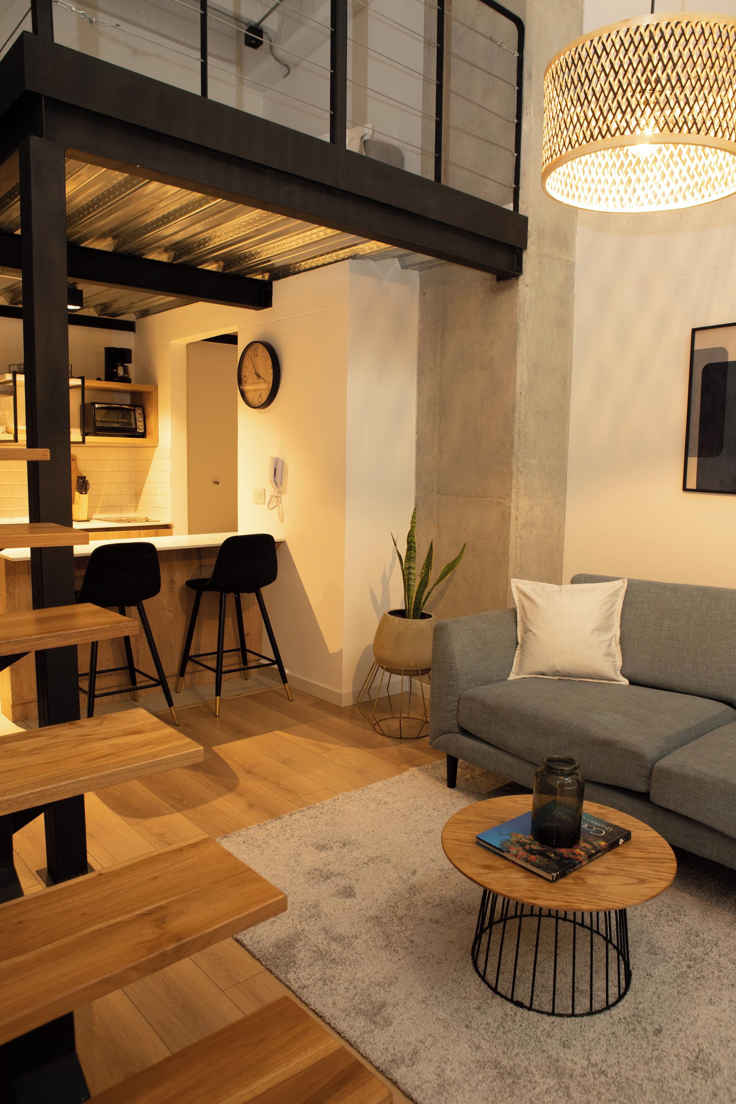 Una sala moderna con sofá, mesa de centro y zona de comedor con sillas y una mesa.