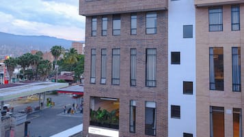 A multi-story building with a mix of brick and white facades, large windows, and a visible entrance with a sign.