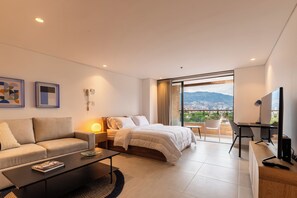 A modern hotel room with a bed, sofa, desk, and a large window offering a city view. - VENTO MOLINO (BELEN)