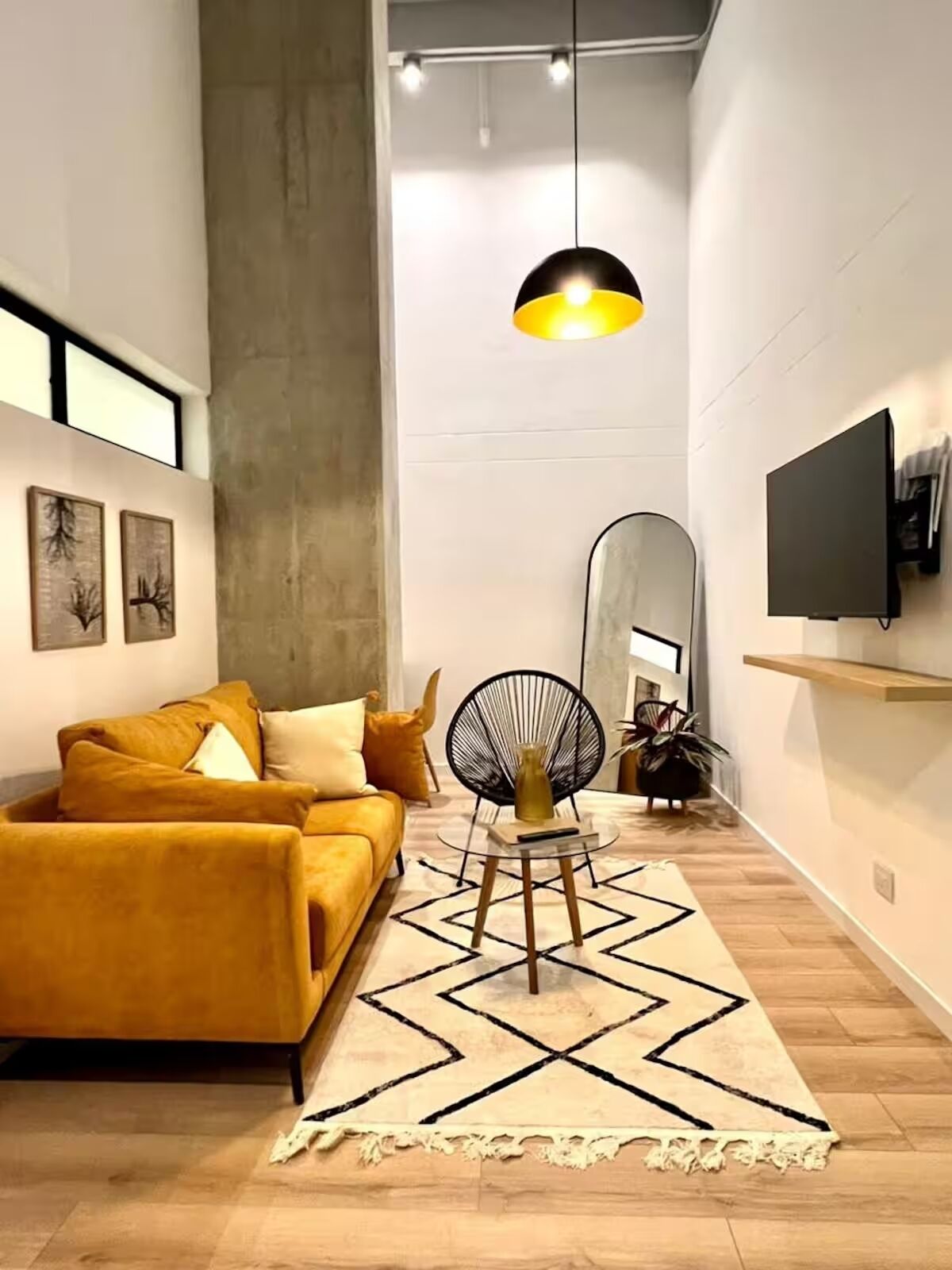 Un salon moderne avec un canapé, un fauteuil rond, une table basse et un grand miroir.