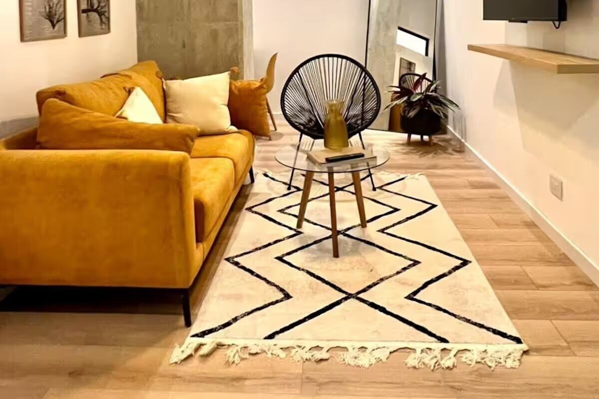 A modern living room with a sofa, a round chair, a coffee table, and a large mirror.