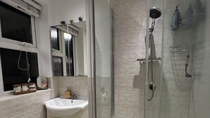 A modern bathroom with a glass-enclosed shower, a sink, and a toilet. - Spacious & Modern Family Gem (London)
