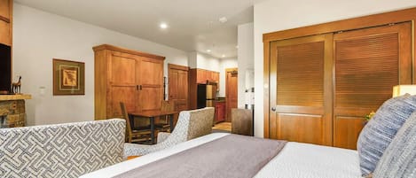 Une chambre d’hôtel avec un lit, un canapé, une table à manger et des armoires en bois.