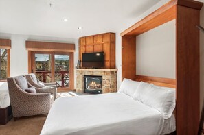 A hotel room with a large bed, a fireplace, a TV mounted on a wooden wall, and a balcony with a view. - Hyatt Residence Club Breckenridge, Main St Station (Breckenridge)