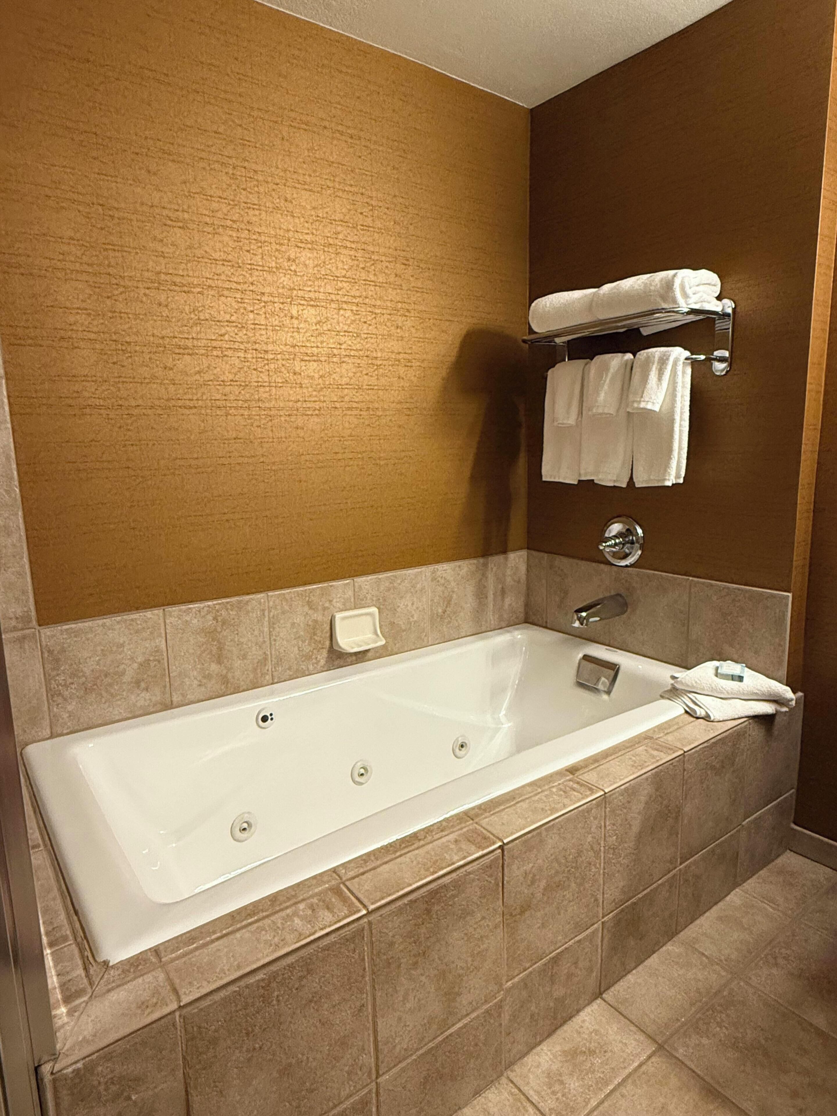 A bathroom with a bathtub, a towel rack with towels, and a soap dish.