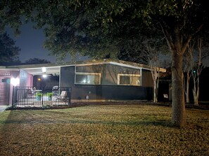Una casa moderna con garaje, un patio cubierto y un césped cuidado.