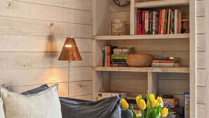 A living room with a grey sofa, a metal vase with flowers, and a wooden bookshelf with various items. - Updated Studio in Elkhorn Village, Sun Valley (Sun Valley)